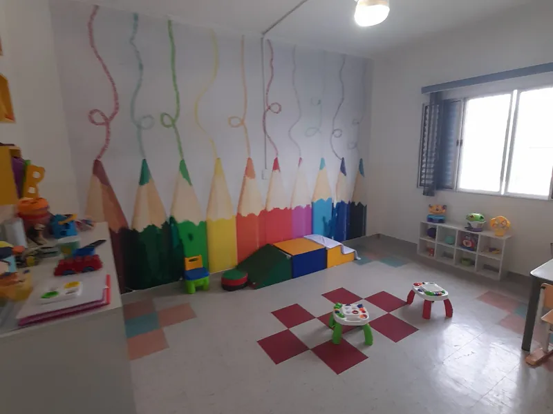 Uma sala da Escola Magia vazia, com lápis de cor pintados na parede e brinquedos ao alcance